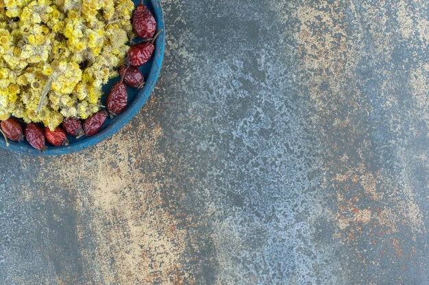 Free photo dried rosehips and flowers on blue plate.