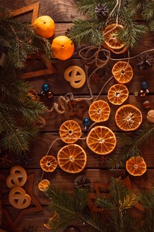 На деревянном столе лежат нарезанные кружками сушеные дольки апельсинов. новогодний flatley