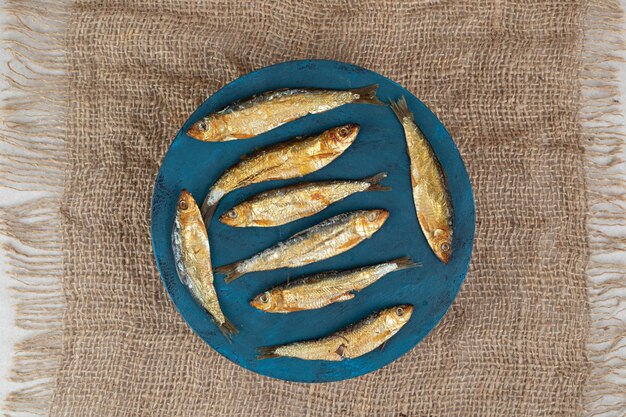 Сушеная рыбка на синей тарелке