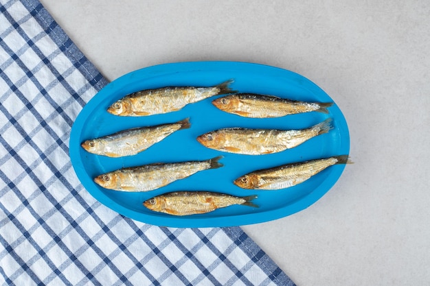 Сушеная рыбка на синей тарелке