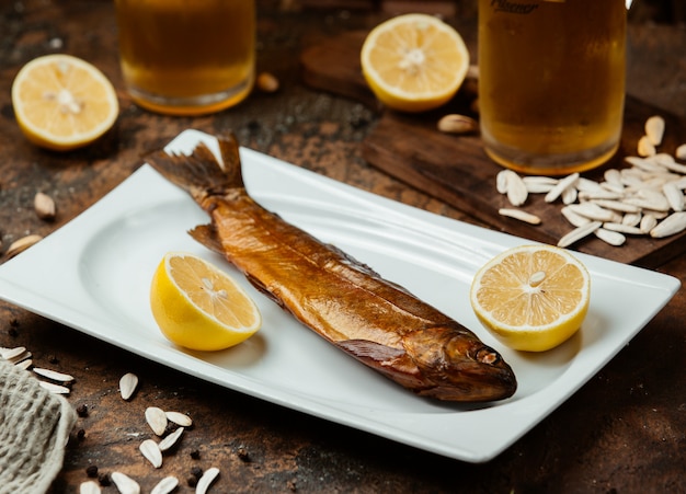 Free photo dried smoked fish served with lemon halves, salty sunflower seeds and beer