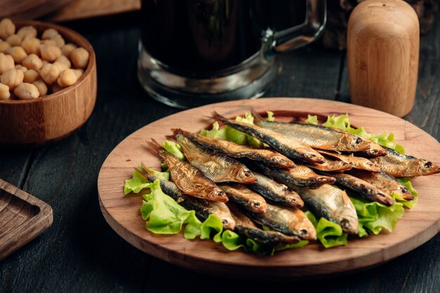 dried smoked sprat layered on lettuce leaves served on round wood platter