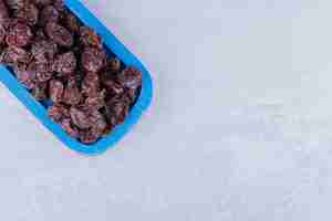 Free photo dried sour cherry plums inside a dish isolated on concrete surface