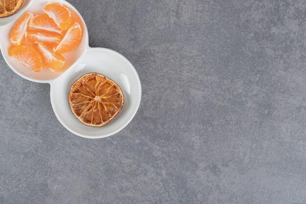 Dried tangerine slices and fresh segments in white bowls. High quality photo