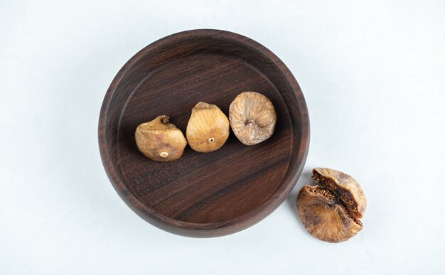 Dried tasty figs on wooden plate.