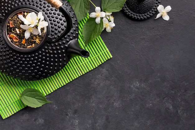 Dried tea herb and white jasmine flower on black background