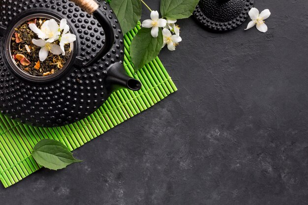 Сушеная чайная трава и белый цветок жасмина на черном фоне