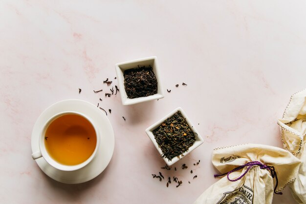 Dried tea herbs bowl with black tea on marble texture backdrop
