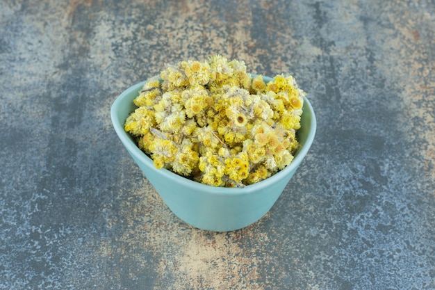 Dried yellow flowers in blue bowl.