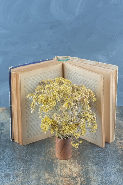 乾燥した黄色い花と大理石の本。