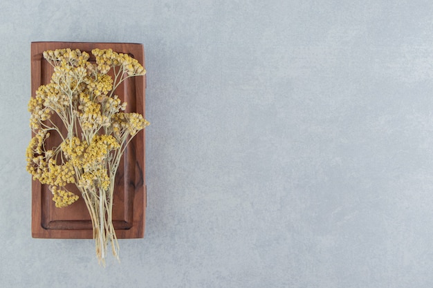 Free photo dried yellow flowers on wooden board.