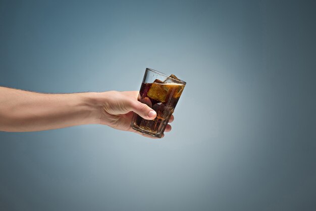 Drink cola in glass with hand