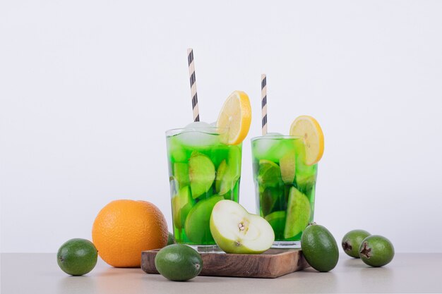 Drinks with apple, feijoa and straw on white