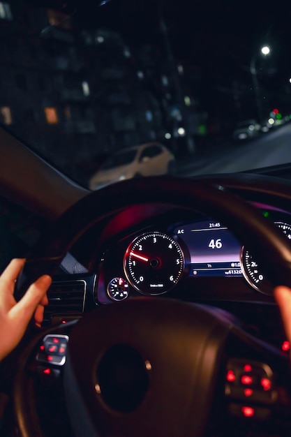 Free photo drivers hands on the steering wheel of a car at night night driving