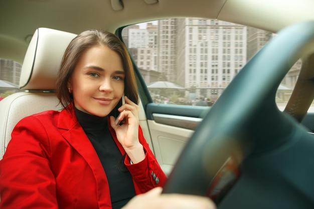 街中を運転。車を運転する若い魅力的な女性。