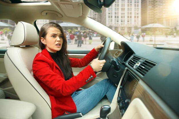 街中を運転。車を運転する若い魅力的な女性。