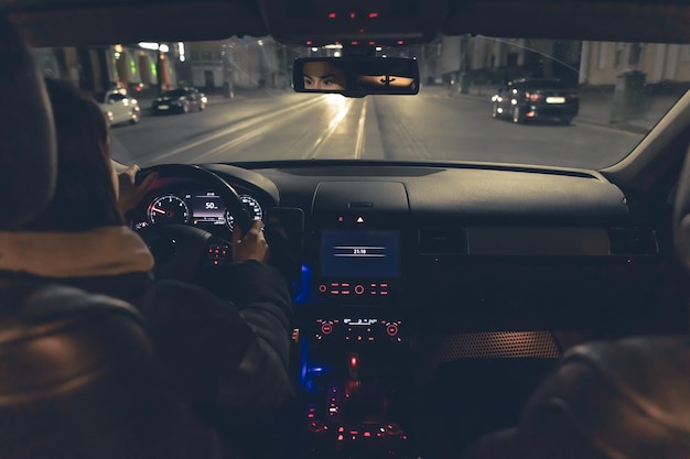 夜に車を運転する女性が街で夜に近代的な車を運転しています