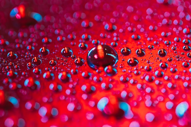 Drop of water bubbles on the surface of red background