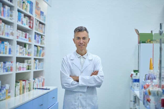 Drugstore. Man in a lab coat standing near the shelves with medicines