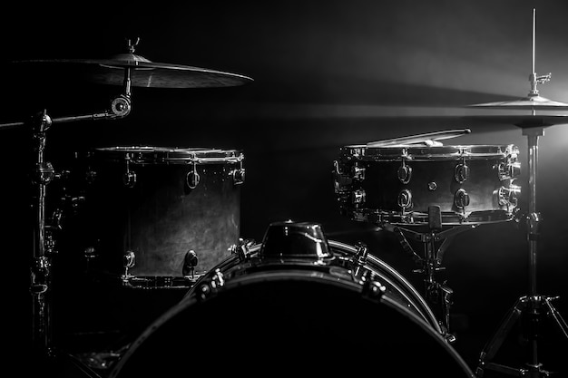 Drum kit on a dark background with stage lighting, copy space.