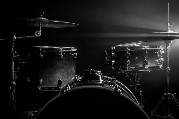 Drum kit on a dark background with stage lighting, copy space.