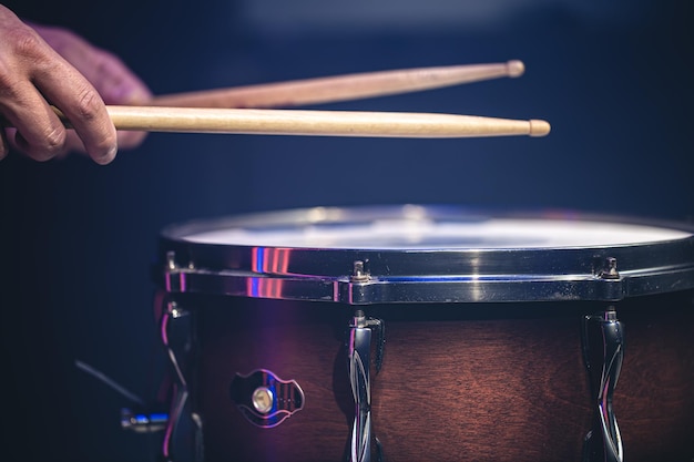 Drummer playing drum sticks on a snare drum on black background