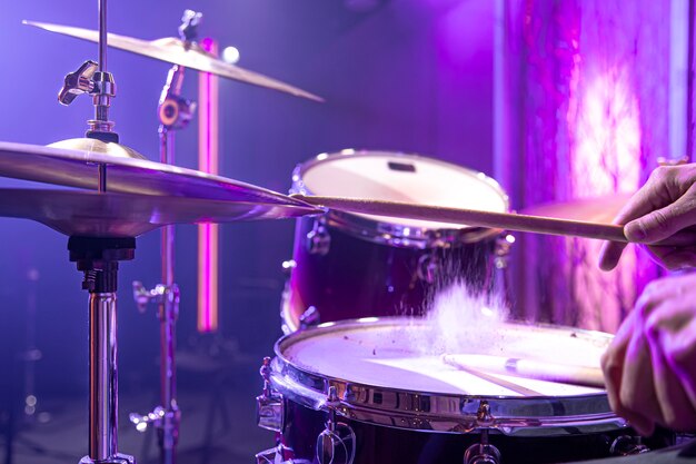 The drummer plays the drum kit in the studio against a beautiful background close up.