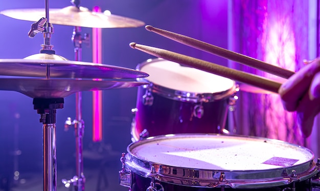 The drummer plays the drum kit in the studio against a beautiful background close up.