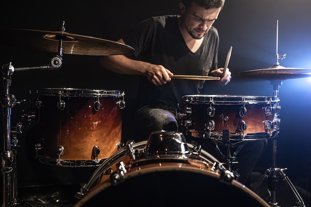 The drummer plays drums while sitting at the drum kit on stage.