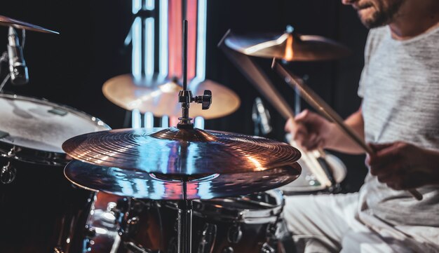 The drummer using sticks while playing on drums during performing.