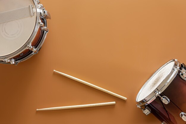 Барабаны и барабанные палочки на коричневом фоне вид сверху