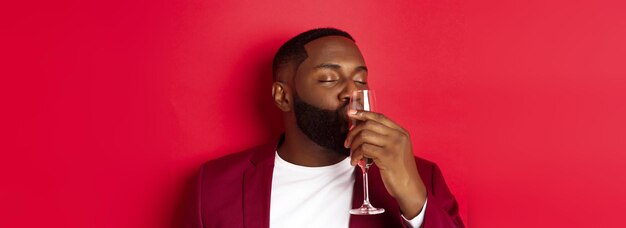 Drunk african american guy kissing glass with champagne celebrating new year enjoying party standing
