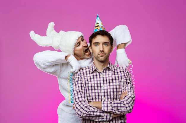 Free photo drunk man and rabbit at birthday party over purple wall.