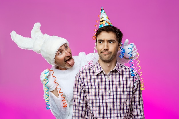 Drunk man and rabbit at birthday party over purple wall.