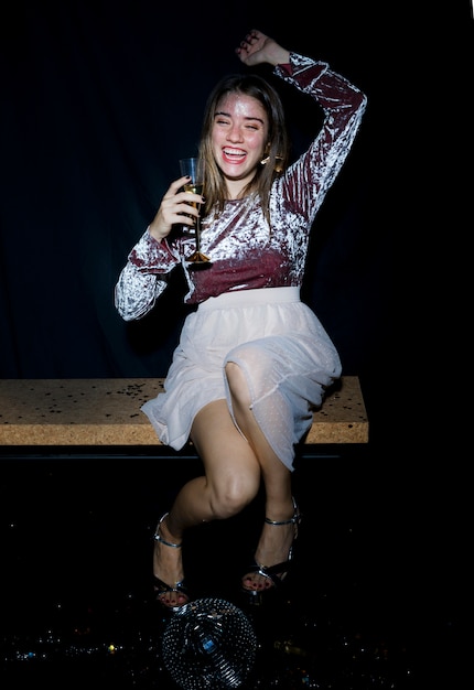 Drunk woman sitting on bench with champagne glass