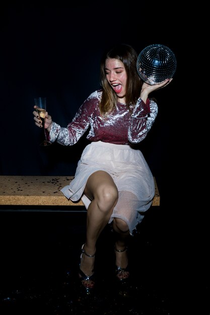 Drunk woman sitting on bench with disco ball 