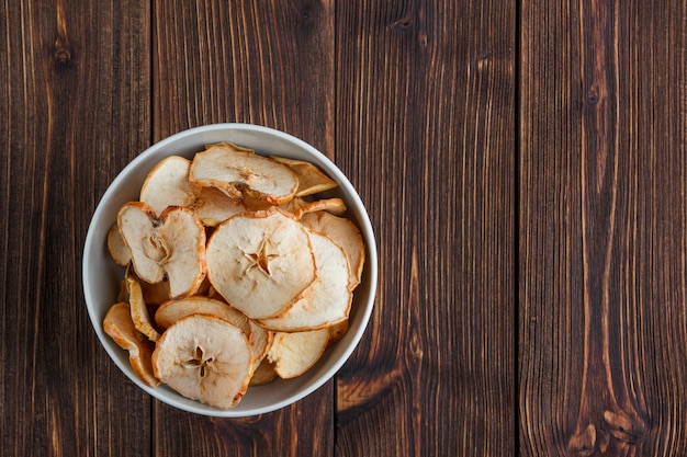 Dry apple in a bowl on a wooden background. top view. space for text