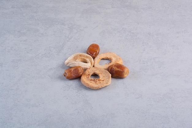 Dry apple slices and dates on concrete background.