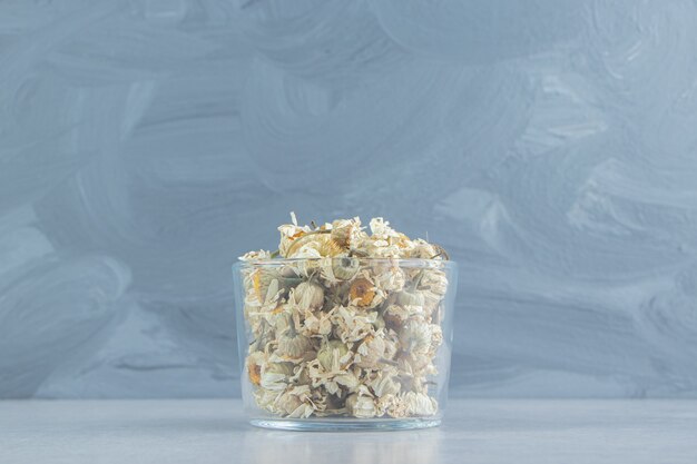 Dry chamomile flowers in glass bowl.  