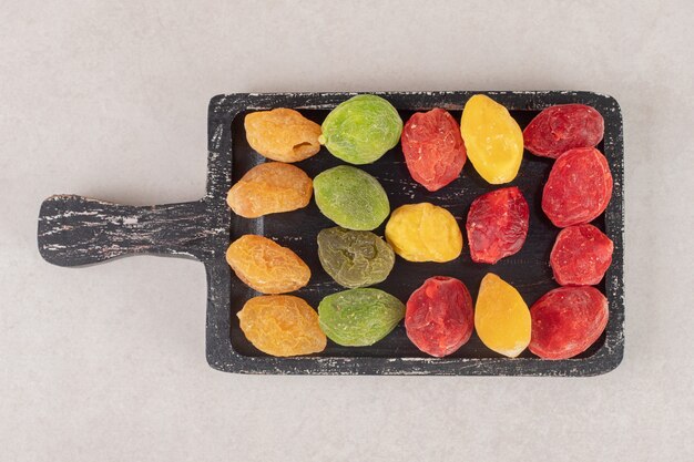Foto gratuita ciliegie colorate secche su un piatto di legno.