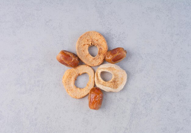 Dry dates and apple slices on concrete background.