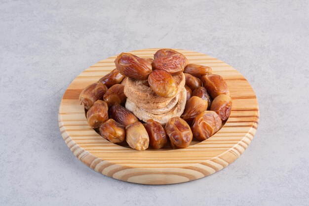 Dry dates and apple slices on concrete surface.