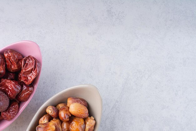 Сушеные финики и ягоды мармелада в керамических мисках.