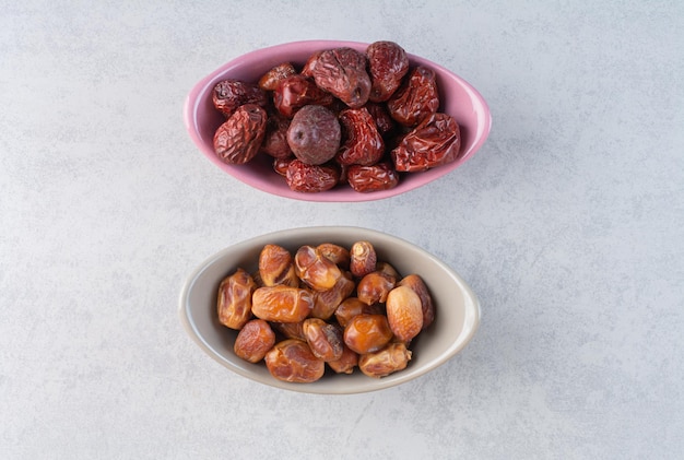 Dry dates and jujube berries in ceramic cups.