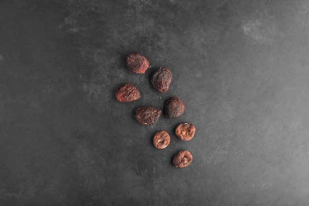 Dry fig and plums in the center of black background, top view.