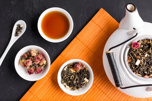 Dry flowers and herb tea on placemat over slate backdrop