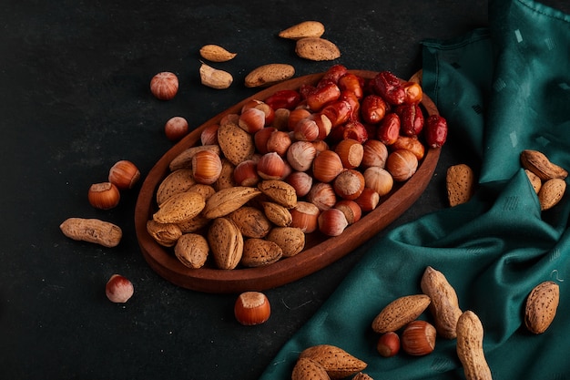 Dry fruit mix in the grocery stock in a wooden platter on green towel. 