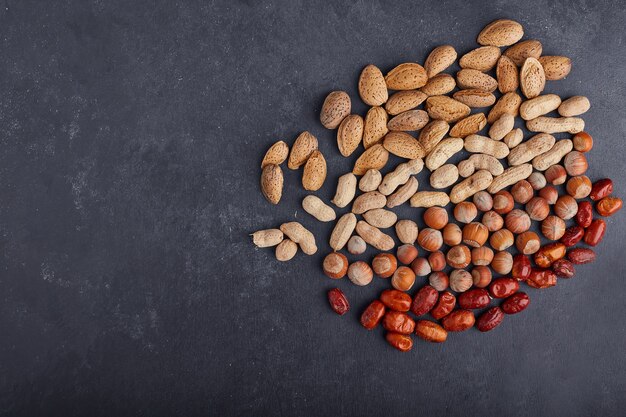 Dry fruits and beans on black surface on the right side. 