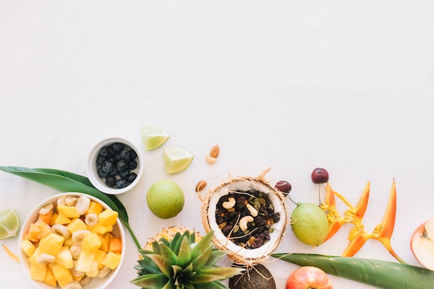 Dry fruits in the coconut with fruits on white backdrop