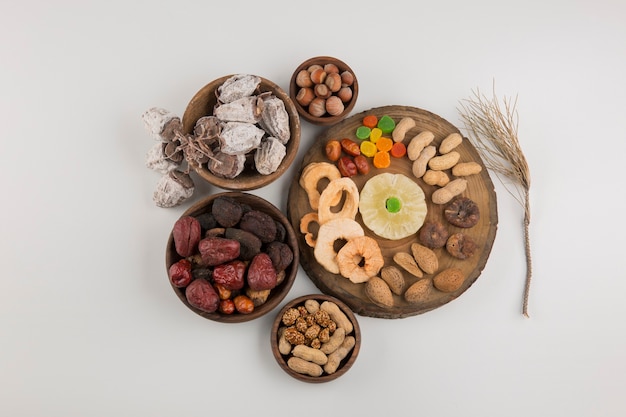 Dry fruits and snacks in multiple wooden platters and saucers in the center